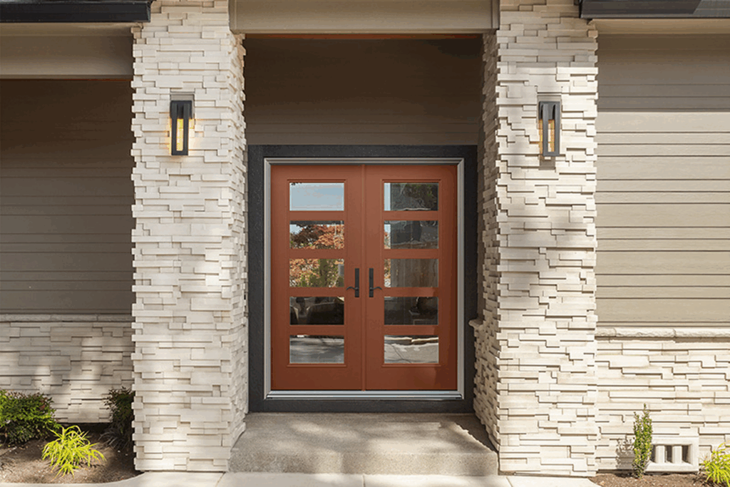 Front entryway of a home featuring double brown wood-grain entry doors with decorative glass panels, matching sidelights, and exterior sconce lights mounted on stone pillars.