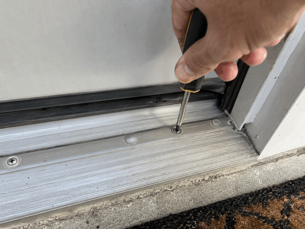 Turning an adjustment screw counterclockwise to raise a door threshold