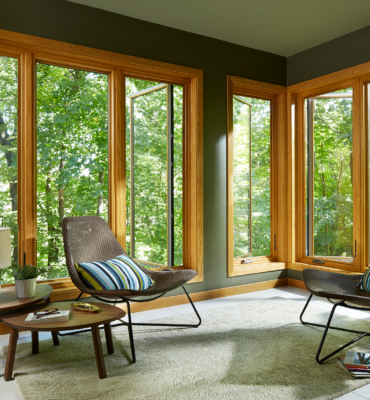 casement windows with wood veneer slightly open to a forested area