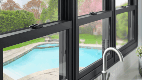 Black Fibrex replacement window with swimming pool view Dark composite window frame looking out onto a backyard patio and swimming pool